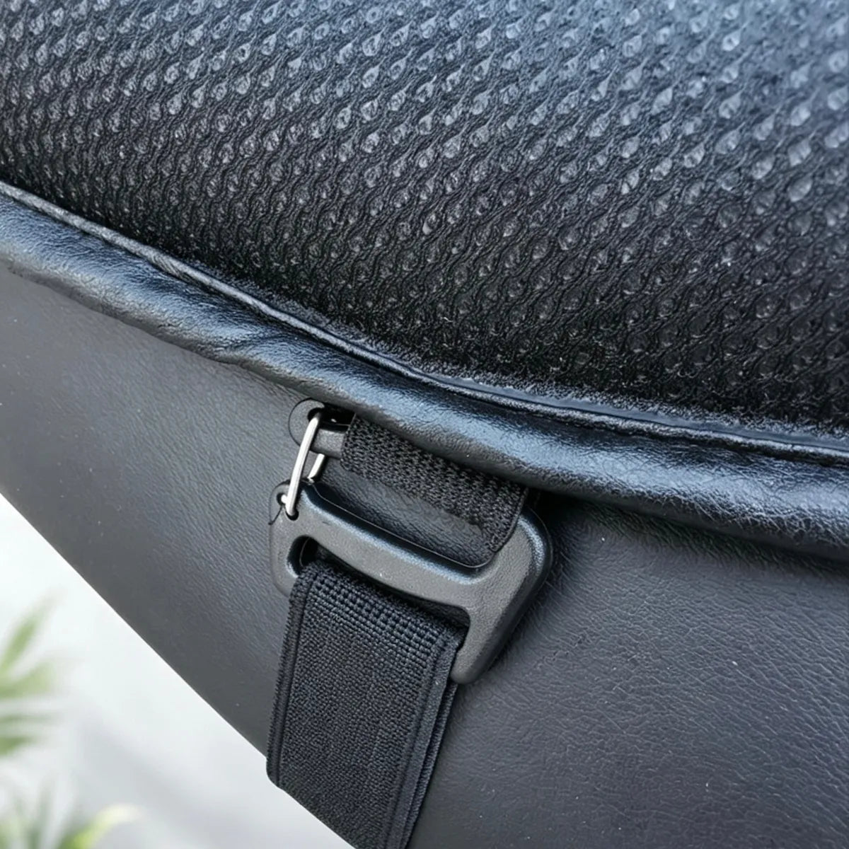 Close-up of a black textured bag with a black strap and buckle closure, showing the material details.
