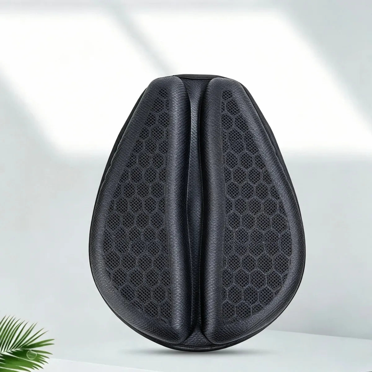 A black teardrop-shaped ergonomic support cushion with a textured honeycomb pattern, shown on a clean white surface with soft window shadows.